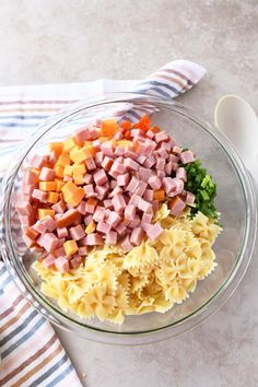 pasta salad with ham and vegetables in a glass bowl