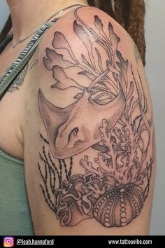 a woman's shoulder with an animal and flowers tattoo on her left side arm