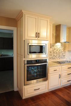 a kitchen with white cabinets and an oven in the center, along with hardwood floors