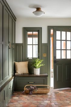 an entryway with green doors and brick flooring in the center, along with a basket full of plants