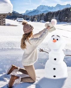 a woman kneeling down next to a snowman