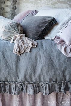 a bed with two pillows on top of it and some ruffles around the edges