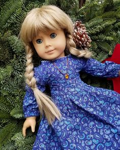 a doll with blonde hair wearing a blue dress and a pine cone in her hand