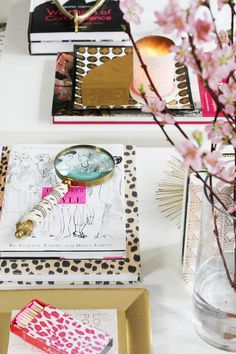 there is a magnifying glass on top of a desk with books and flowers