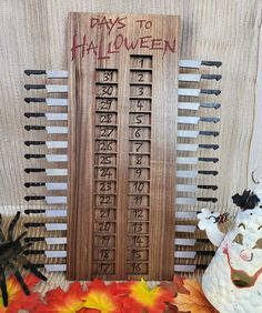 a wooden board with numbers and letters on it next to fall leaves, pumpkins and other decorations