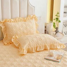 a bed with yellow ruffled sheets and pillows