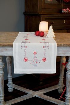 a white table topped with a candle and christmas decorations on top of a wooden table