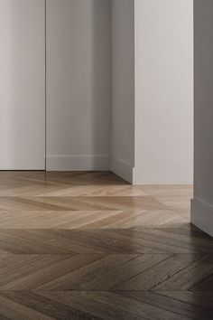 an empty room with white walls and wood floors