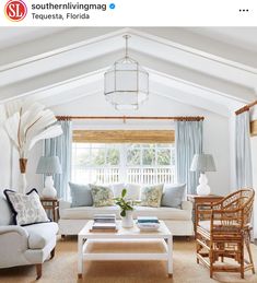 a living room with white furniture and blue curtains