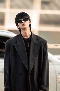 a man wearing sunglasses standing in front of a car