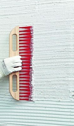 a person in white gloves is painting a wall with red paint on the side of it