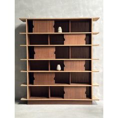 a wooden shelf with two white vases sitting on it's sides, against a gray wall