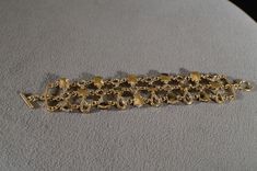 I am offering this fabulous vintage yellow gold tone bracelet. This piece is truly gorgeous, and it has the following features: * beautiful vintage bracelet * yellow gold tone * glass stone * amber * etched * toggle closure * 7 inches in length This is a fantastic and classic piece. There is tons of sparkle and shine with this piece. It will beautifully complement your upcoming fashion season. Buyer pays all shipping and handling. 11/06 Antique Gold Bracelet Strap Jewelry, Gold Costume Jewelry Bracelet, Vintage Handmade Gold Bracelets, Gold Metal Bracelet With Clasp, Handmade Vintage Gold Bracelets, Adjustable Gold Bracelet For Evening, Adjustable Gold Bracelets For Evening, Vintage Gold Bracelet With Clasp, Vintage Adjustable Charm Bracelet For Formal Occasions