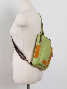 a white mannequin with a green purse on it's back and brown straps