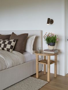 a bedroom with a bed, nightstand and flower pot on the side table in front of it