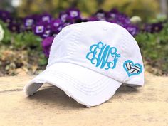 a white baseball cap with the word custom colors on it sitting in front of purple flowers