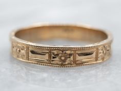 an antique gold wedding band with flowers on it