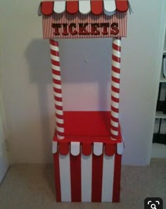 a red and white striped chair with a ticket booth