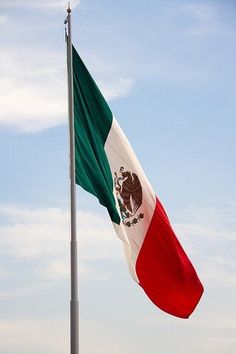 the mexican flag is flying high in the sky