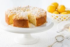 a cake on a white plate with lemons in the background