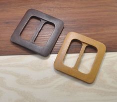 two square wooden buckles sitting on top of a wood floor next to each other