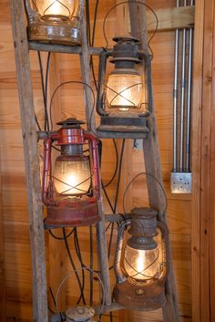 three old fashioned lanterns are on a ladder in a room with wood paneled walls