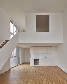 an empty room with wooden floors and white cabinets in the center, stairs leading up to the second floor