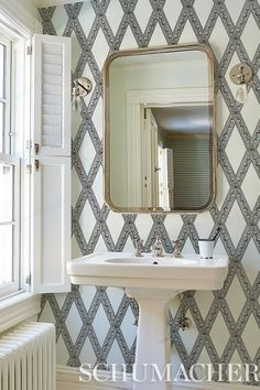 a white pedestal sink sitting under a bathroom mirror