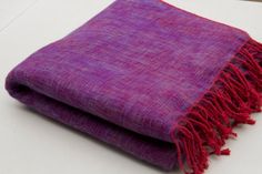 a purple and red blanket sitting on top of a white table