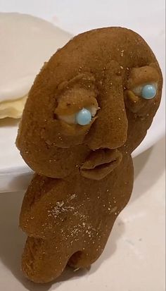 a close up of a doughnut with eyes and mouth on a plate next to a spoon