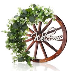 a wooden wheel with the word welcome written on it and flowers in front of it