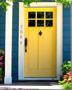 a blue house with yellow front door and shutters on the windows is decorated with potted plants