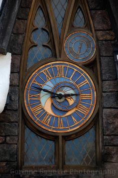 a large clock mounted to the side of a brick building next to a tall window