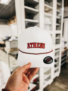 "Show off your love for the classic city of Athens and the Georgia Bulldogs with our high-quality custom Athens hat! This white, red, and black Georgia hat is the perfect accessory for any Bulldogs fan who wants to show off their pride for the city of Athens and the beloved football team. Made with high-quality materials, this hat is both stylish and comfortable. It features a classic design with a white base and the iconic red and black colors of the Bulldogs. The word \"Athens\" is embroidered Casual Red Adjustable Hat Bands, Adjustable Fitted Hat With Curved Brim For Game Day, Adjustable Flat Bill Hat For Game Day, Adjustable Curved Brim Fitted Hat For Game Day, Game Day Flat Bill Adjustable Hat, Adjustable Fitted Cap For Game Day, Classic Adjustable Hats For Sports Events, Adjustable Curved Brim Hats For Game Day, White Adjustable Fitted Hat With Curved Brim