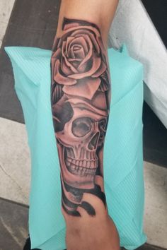 a person with a rose and skull tattoo on their arm