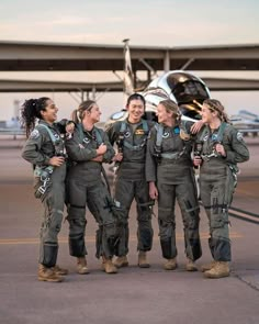 four female pilots standing in front of an airplane and talking to each other on the tarmac