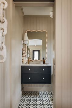 a bathroom with a sink, mirror and light on the wall in it's doorway