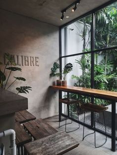 the inside of a restaurant with tables and plants on the windowsills, along with wooden benches