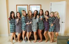 a group of women standing next to each other wearing matching plaid robes and holding champagne flutes