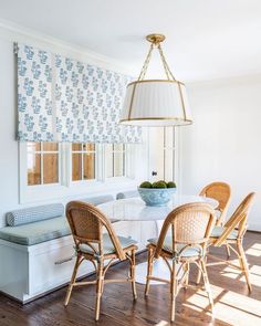 a dining room table with four chairs and a bench in front of the window,