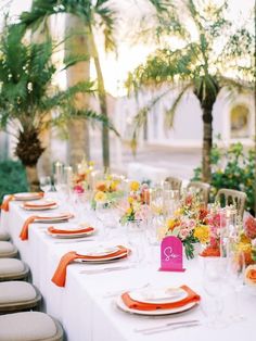 a long table with orange and white place settings