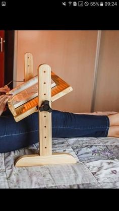 a woman sitting on top of a bed next to a wooden frame with an object in it