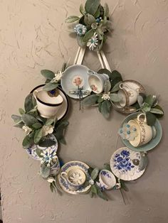 a wreath made out of teacups and saucers hanging on the side of a wall