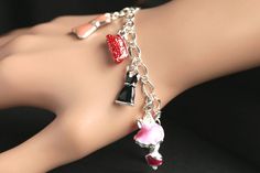 A collection of silver plated and colorfully enameled fashion themed charms have been dispersed around a shimmering silver plated bracelet chain in this handmade charm bracelet. This fashion charm bracelet is then completed with a lobster clasp and a 1/2 inch of chain at the end for adjustable sizing. Charms in this bracelet include three enameled pink dress charms, an enameled black dress charm, two enameled shoe charms, two enameled purse charms, and a detailed corset charm. ● Sizing ● To dete Cute Silver Charm Bracelet Bangle, Cute Silver Bangle Charm Bracelet, Cute Silver Charm Bracelet For Party, Silver Alloy Charm Bracelet For Party, Nickel-free Enamel Bracelet As A Gift, Cute Silver Bracelets For Jewelry Making, Silver Enamel Charm Bracelets, Silver Charm Bracelets With Enamel, Silver Enamel Bracelets With Charms