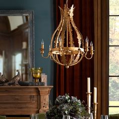 a fancy chandelier hangs over a dining room table with place settings on it