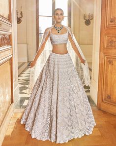 This lehenga set features delicate pearl and diamonte embroidery in a scalloped pattern. The fully embroidered blouse shows tassels at the waist and is paired with four sided embroidered dupatta.From Seema Gujral's Love Notes From Paris Collection DELIVERY TIMEPlease allow 8-12 weeks for your outfit to arrive. FABRIC DETAILSNet Professional cleaning only. Ivory Lehenga, Seema Gujral, Sangeet Outfit, White Lehenga, Scallop Pattern, Floral Lehenga, Padded Blouse, Embroidered Lehenga, Lehenga Blouse