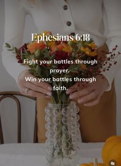 a woman holding a vase filled with flowers on top of a table