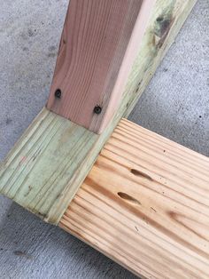 a wooden bench sitting on top of a cement floor next to a building with wood slats