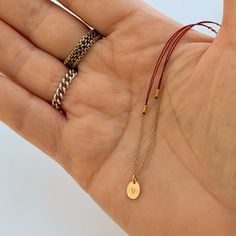 A very delicate necklace featuring double red thread strands, tiny golden nuggets on the sides, an oval simple shape pendant with a little piece of 14K gold fill chain on the bottom.The pendant is custom stamped with the letter of your choice. Please, type the letter you want to be stamped on your pendant at check-out!∙ Only 1 letter permitted.∙ We use only capital letters.In many cultures, the color red is traditionally used as a symbol of protection, good luck, or blessing. In my native Argent Dainty Oval Pendant Chain Necklace As Gift, Minimalist Oval Necklaces With Gold Chain, Gift Oval Pendant Chain Necklace With Adjustable Chain, Delicate Oval Pendant Chain Necklace As Gift, Gold Plated Chain Necklace With Oval Pendant, Red Gold Chain Necklace For Gifting, Oval Chain Necklace With Adjustable Chain For Gift, Dainty Oval Chain Necklace For Gift, Dainty Oval Chain Necklace As Gift