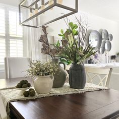 a dining room table with vases and plants on it